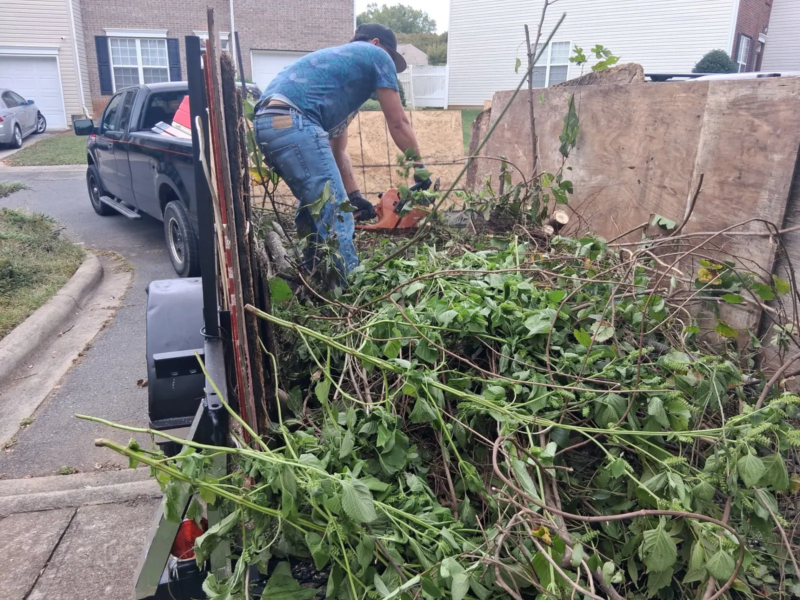 Crew member cutting brush and loading yard debris into a trailer in a Charlotte, NC neighborhood